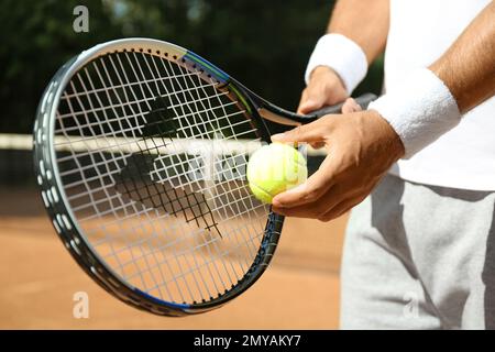 Ein Sportler, der sich darauf vorbereitet, Tennisball auf dem Platz zu servieren, Nahaufnahme Stockfoto