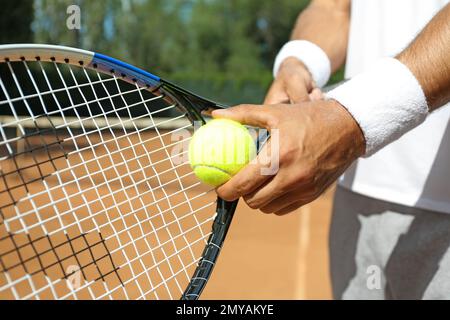 Ein Sportler, der sich darauf vorbereitet, Tennisball auf dem Platz zu servieren, Nahaufnahme Stockfoto