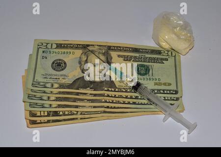 20-Dollar-Scheine mit Spritze und Pillen auf weißem Hintergrund Stockfoto
