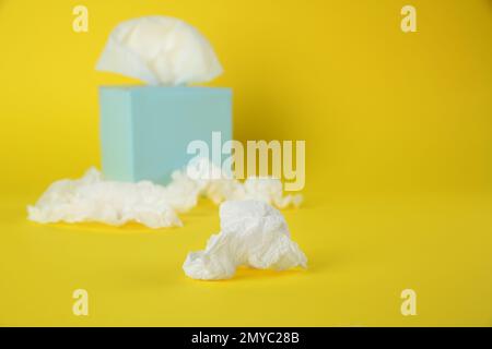 Gebrauchte Papiertücher und Schachtel auf gelbem Hintergrund. Platz für Text Stockfoto
