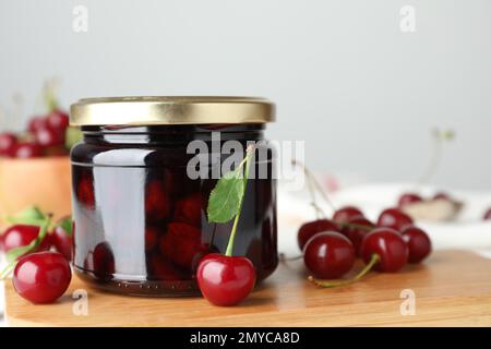 Eingelegte Kirschen und frisches Obst auf Holzbrett, Nahaufnahme Stockfoto