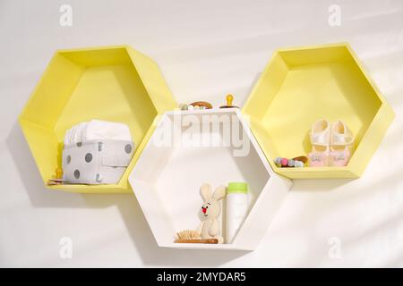 Sechseckige Regale mit Spielzeug und Kinderzubehör an weißen Wänden. Innendesign Stockfoto