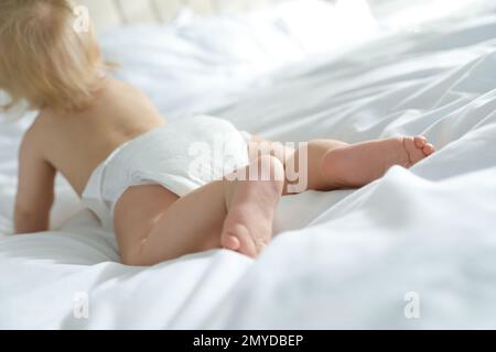 Süßes kleines Baby in Windel im Schlafzimmer, konzentriere dich auf die Beine Stockfoto