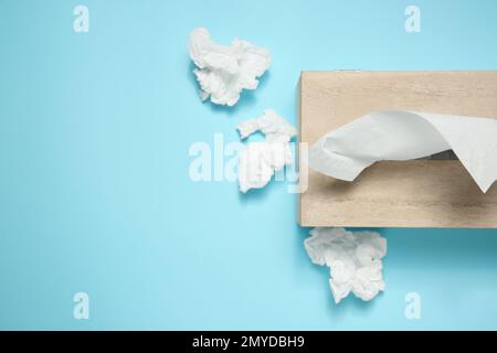 Gebrauchte Papiertücher und Holzhalter auf hellblauem Hintergrund, flach verlegt. Platz für Text Stockfoto
