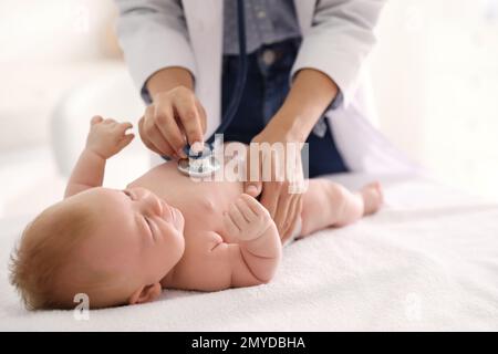 Doktor untersucht süßes Baby mit Stethoskop drinnen, Nahaufnahme. Gesundheitsfürsorge Stockfoto