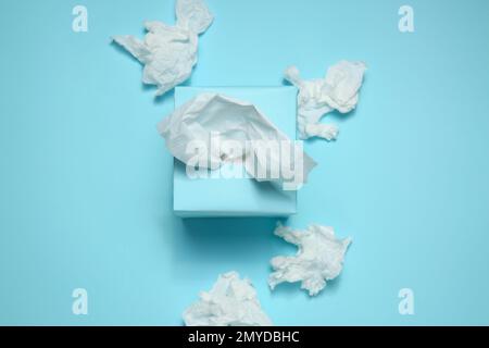 Gebrauchte Papiertücher und Schachtel auf hellblauem Hintergrund, flach liegend Stockfoto