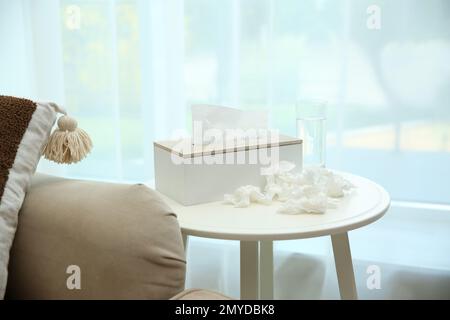 Gebrauchte Papiertücher, Halter und Wasser auf dem Tisch in Innenräumen Stockfoto