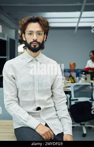 Vertikales Foto eines Geschäftsmannes im Büro. Hart arbeitender und geschäftiger Typ. Stockfoto