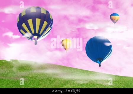 Traumwelt. Heißluftballons in rosa Himmel über grüner Wiese Stockfoto