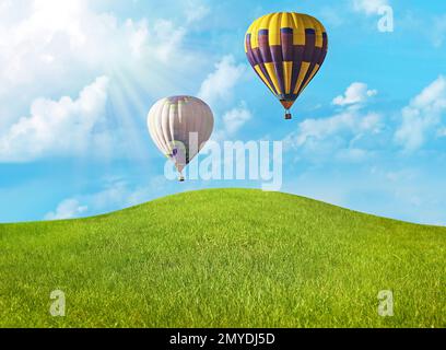Traumwelt. Heißluftballons am Himmel mit Wolken über grüner Wiese Stockfoto