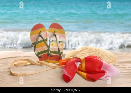 Verschiedene Strandzubehör auf Sand in der Nähe des Ozeans Stockfoto