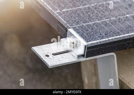 Halterung zur Montage von Solarmodulen. Montage eines Solarpaneels auf dem Dach eines Wohngebäudes, Wassertropfen nach Regen, grüne Energie Stockfoto