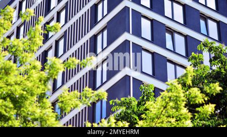 Ökologische Wohnarchitektur. Ein modernes Wohngebäude in der Nähe von Bäumen. Ökologie und umweltfreundliches Leben in der Stadt, städtisches Umweltkonzept. Stockfoto