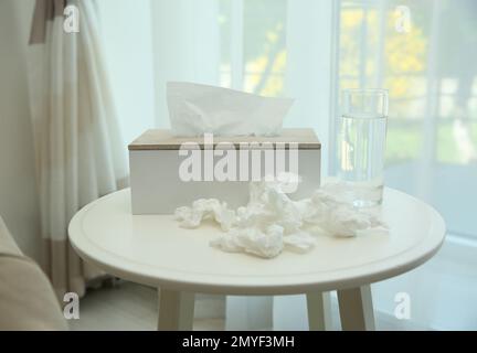 Gebrauchte Papiertücher, Halter und Wasser auf dem Tisch in Innenräumen Stockfoto