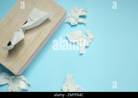 Gebrauchte Papiertücher und Holzhalter auf hellblauem Hintergrund, flach verlegt. Platz für Text Stockfoto