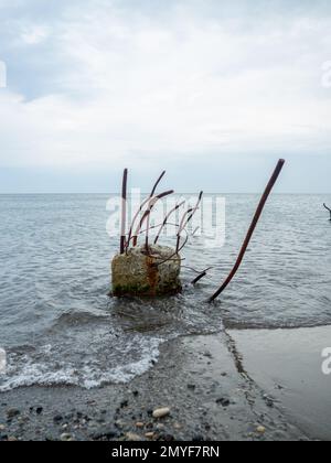 Stahlbeton, der aus dem Wasser ragt. Reste der Struktur. Verlassen. Anker auf See. Ein Haufen, der in den Meeresgrund getrieben wird. Ruiniert Stockfoto