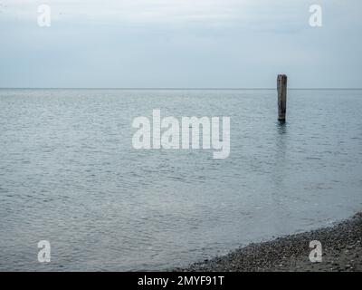 Stahlbetonhaufen, der aus dem Wasser ragt. Überreste einer alten Brücke im Meer. Ruinierter Pier. Verlassen. Anker auf See. Zerstörtes Gebäude. Stockfoto