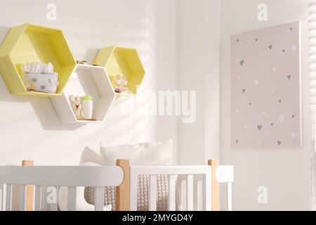 Sechseckige Regale an der weißen Wand im Kinderzimmer. Innendesign Stockfoto