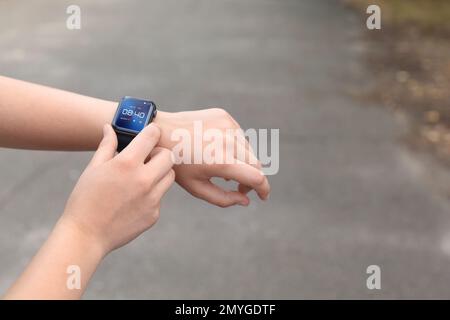 Frau, die die Zeit oder Herzfrequenz im Freien mit einer Smartwatch überwacht, Nahaufnahme Stockfoto