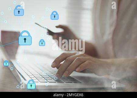 Informationssicherheit. Eine junge Frau, die ihren Laptop drinnen am Tisch benutzt, Nahaufnahme Stockfoto