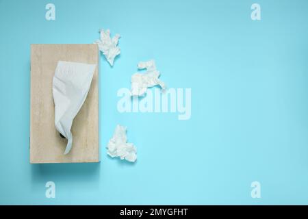 Gebrauchte Papiertücher und Holzhalter auf hellblauem Hintergrund, flach verlegt. Platz für Text Stockfoto
