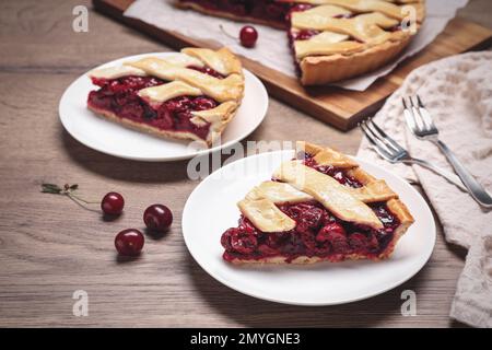 Scheiben köstlicher frischer Kirschkuchen, serviert auf einem Holztisch, Nahaufnahme Stockfoto