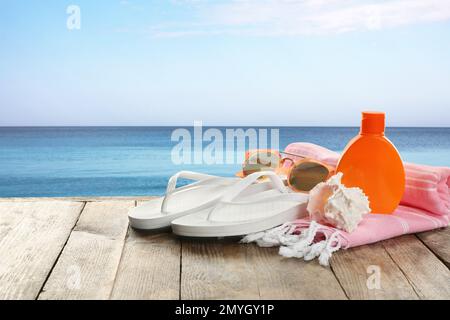 Strandaccessoires auf Holzfläche nahe dem Meer, Platz für Text Stockfoto