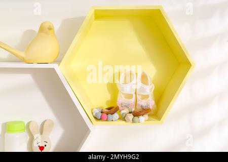 Sechseckige Regale mit Spielzeug und Kinderzubehör an weißen Wänden. Innendesign Stockfoto