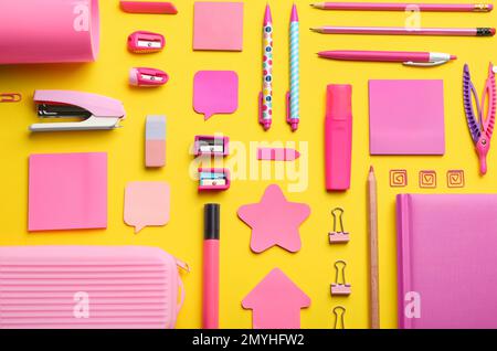 Flache Laienzusammensetzung mit pinkfarbenem Schulpapier auf gelbem Hintergrund. Zurück in die Schule Stockfoto