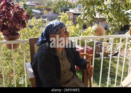 Eine ältere Frau, die an einem Herbsttag im Nordirak auf ihrer Veranda sitzt. Stockfoto