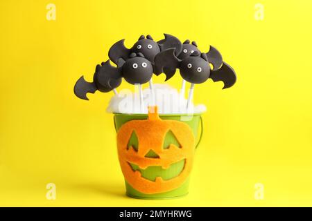 Köstlicher Kuchen in Fledermausform auf gelbem Hintergrund. Halloween-Leckerbissen Stockfoto