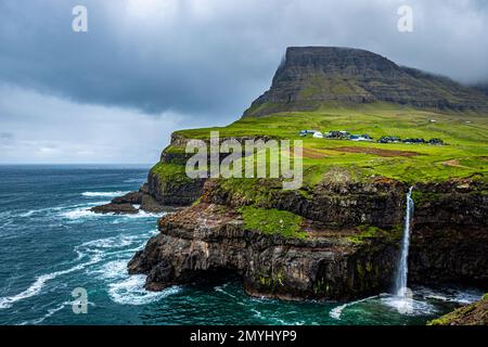 Gasadalur Dorf und Múlafossur Wasserfall, der in den Atlantischen Ozean auf Vagar, Färöer Inseln von einem der bekanntesten Aussichtspunkte führt Stockfoto