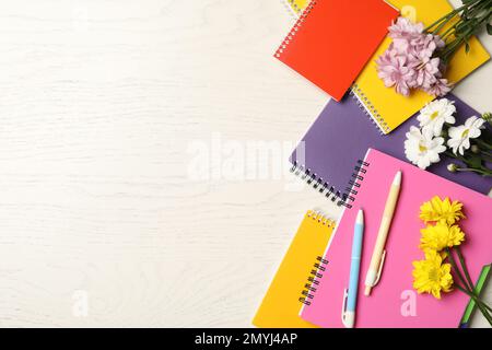 Set aus bunten Schreibwaren und Blumen auf weißem Holztisch, flach liegend mit Platz für Text. Lehrertag Stockfoto