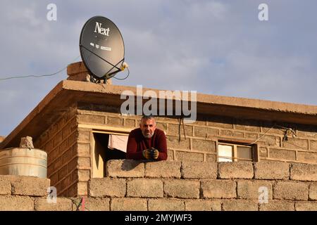 Ein kurdischer Mann lehnt sich auf den Balkon seines Hauses in einem nordirakischen Dorf Stockfoto