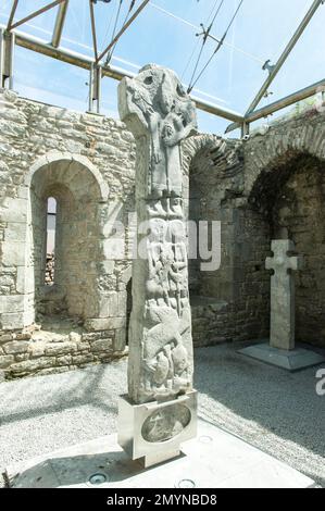 Irokische Kirche, dekoriertes irisches Hochkreuz aus dem Mittelalter, Statuen von Mönchen, Doorty Cross, Ostseite, in der verglasten Kathedrale von Kilfenora Stockfoto