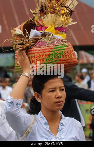 Frau mit Opfern in einem gewebten Korb, auf dem Kopf getragen, Hindu-Prozession, buddhistischer Hindu-Tempelkomplex Pura Ulun Danu Bratan, Candi Kuning, Stockfoto