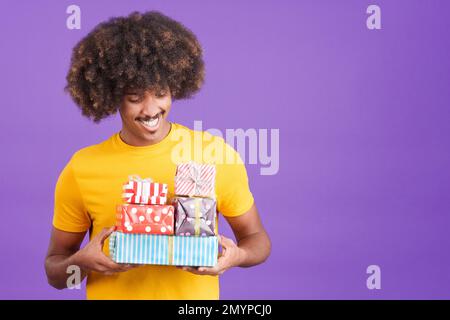 Ein afrikanischer Mann lächelt mit vielen Geschenken in den Händen Stockfoto