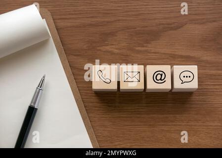 Verschiedene Kontaktansätze. Symbol für Telefon, E-Mail, Post und Chat auf einem hölzernen Würfel. Stockfoto