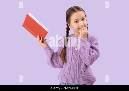 Kleines Mädchen mit Bücherknöpfen auf lila Hintergrund Stockfoto