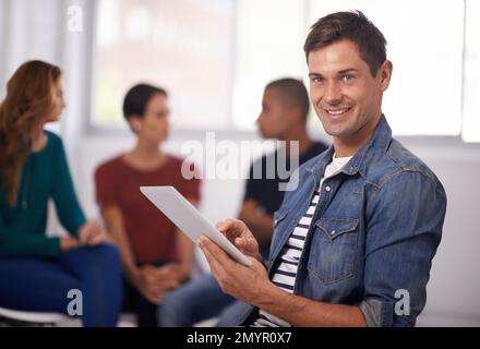 Ich leite dieses Projekt. Porträt eines jungen Geschäftsmanns mit einem digitalen Tablet und seinen Kollegen im Hintergrund. Stockfoto