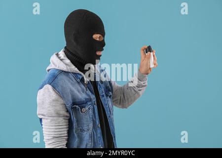 Dieb mit Pfefferspray zur Selbstverteidigung auf blauem Hintergrund Stockfoto