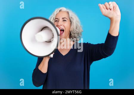 Reife Frau hebt die Faust und protestiert mit einem Lautsprecher Stockfoto