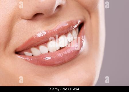 Das ist ein perfektes Lächeln. Ein perfektes Lächeln der Frau vor grauem Hintergrund. Stockfoto