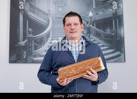 Flintbek, Deutschland. 21. Januar 2023. Malte Fiebing-Petersen, Vorsitzender des Deutschen Titanischen Vereins, hält ein Stück des Geländers des Titanic Salons, wo Teile des Films gedreht wurden. Ein Bild des Geräts ist im Hintergrund zu sehen. Der Film Titanic wurde vor 25 Jahren am 08. Februar 1998 vorgestellt. Kredit: Axel Heimken/dpa/Alamy Live News Stockfoto