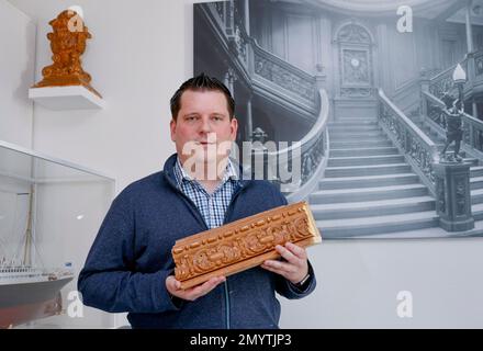 Flintbek, Deutschland. 21. Januar 2023. Malte Fiebing-Petersen, Vorsitzender des Deutschen Titanischen Vereins, hält ein Stück des Geländers des Titanic Salons, wo Teile des Films gedreht wurden. Ein Bild des Sets ist im Hintergrund zu sehen, sowie ein weiteres Stück Geländer auf einem Regal. Der Film Titanic wurde vor 25 Jahren am 08. Februar 1998 vorgestellt. Kredit: Axel Heimken/dpa/Alamy Live News Stockfoto