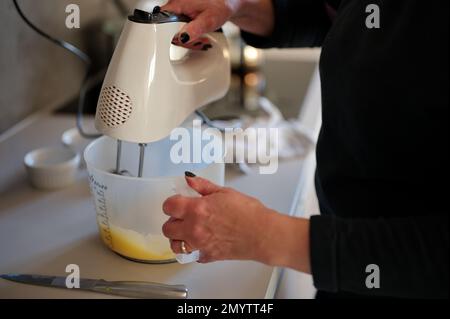 Mittelteil einer Frau, die Kuchen mit dem Mixer zubereitet Stockfoto