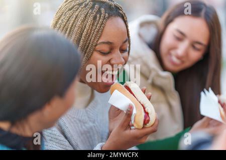 Afrikanische Frau, die Hot Dog mit Freunden in einem Park isst Stockfoto