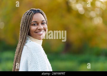 Afrikanische Frau dreht sich um, um in die Kamera zu lächeln Stockfoto