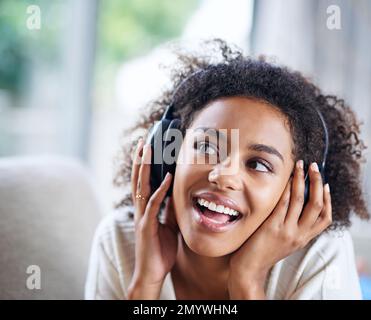 La la... eine junge Frau mit Kopfhörern, die zu Hause Musik hört. Stockfoto