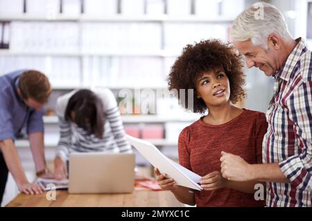Ich bekomme Input von einer alten Hand. Eine attraktive junge Geschäftsfrau, die einen Kollegen um Rat bittet. Stockfoto